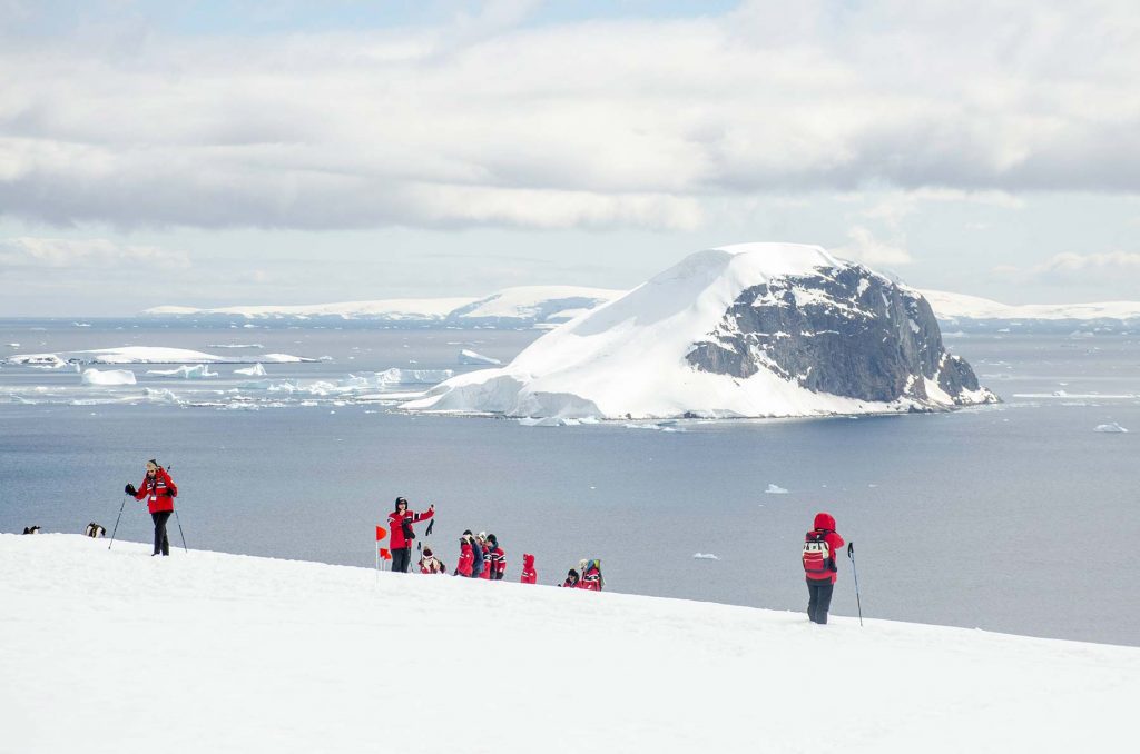 Danco Island in Antarctica with expedition members hiking on a snowy slope