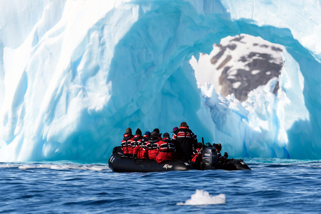 Snowy mountains and deep blue waters of Cierva Cove, Antarctica, with a research station visible on the shore.