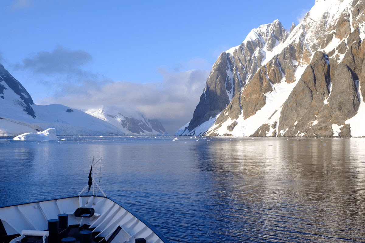 Expedition ship navigates the Lemaire Channel with mountains and ice formations